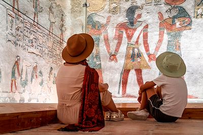 Une mère et son fils observent des hiéroglyphes dans une pyramide  - Egypte