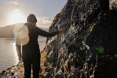 Femme touchant la roche sur les îles Féroé