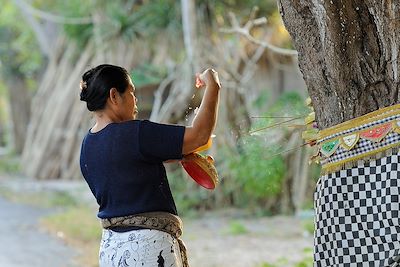 Une femme dépose des offrandes au pied d'un arbre - île de Nusa Lembongan - Bali - Indonésie