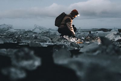 Un homme explore un bloc de glace cristalline à la lumière d'une lampe frontale
