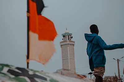 Homme de dos sur un bateau avec drapeau au Sénégal