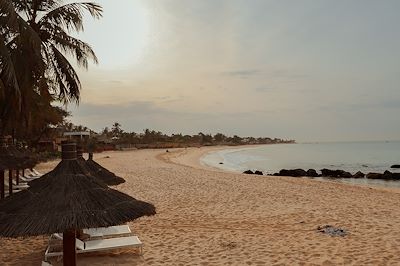 Plage avec transats et palmiers sur la côte au Sénégal